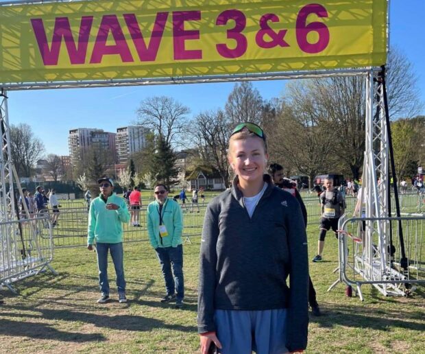 Hannah pictured at another running event below a banner.