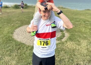 Dan at a running event with his little boy on his shoulders.