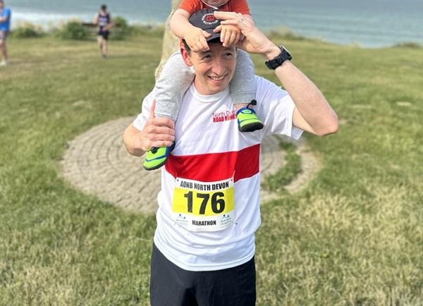 Dan at a running event with his little boy on his shoulders.