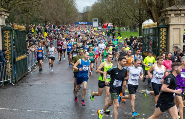 Runners at the Bath Half Marathon running along the road being cheered by spectators.