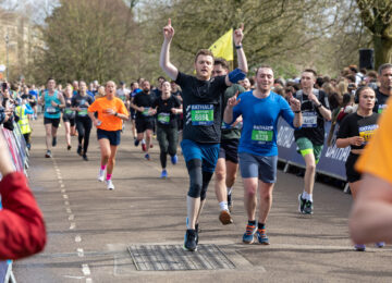 Runners at the Bath Half Marathon running along the road being cheered by spectators.