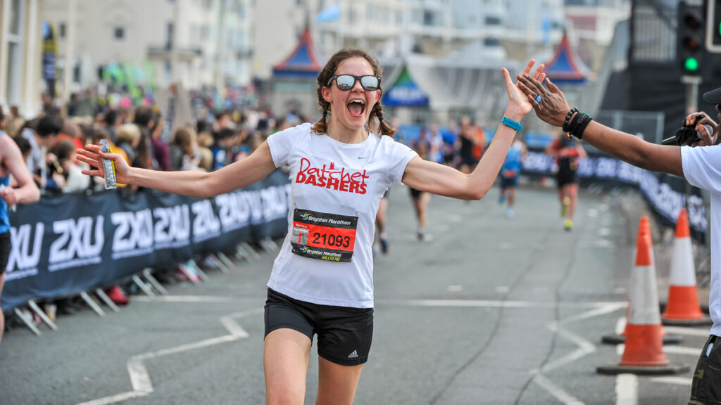 A runner at the Brighton Marathon high fiving a spectator.
