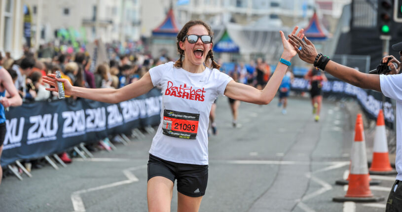 A runner at the Brighton Marathon high fiving a spectator.