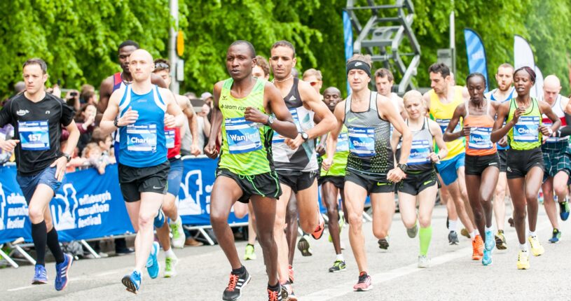 Runners at the Edinburgh Marathon running along the road being cheered by spectators.