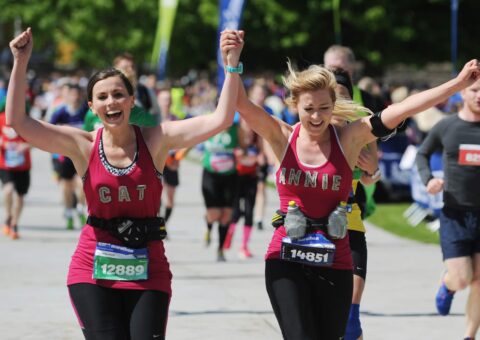 Runners at the Edinburgh Marathon running along the road being cheered by spectators.