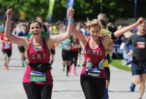 Runners at the Edinburgh Marathon running along the road being cheered by spectators.