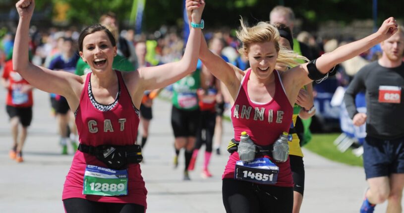 Runners at the Edinburgh Marathon running along the road being cheered by spectators.